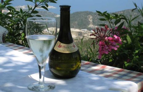 Vinflaska från grekland står på ett bord med ett glas breddvid