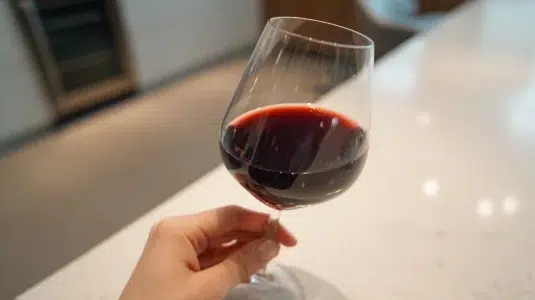 Glas med mörkt nebbiolo-vin som visar tanninstruktur, hållet mot ljuset